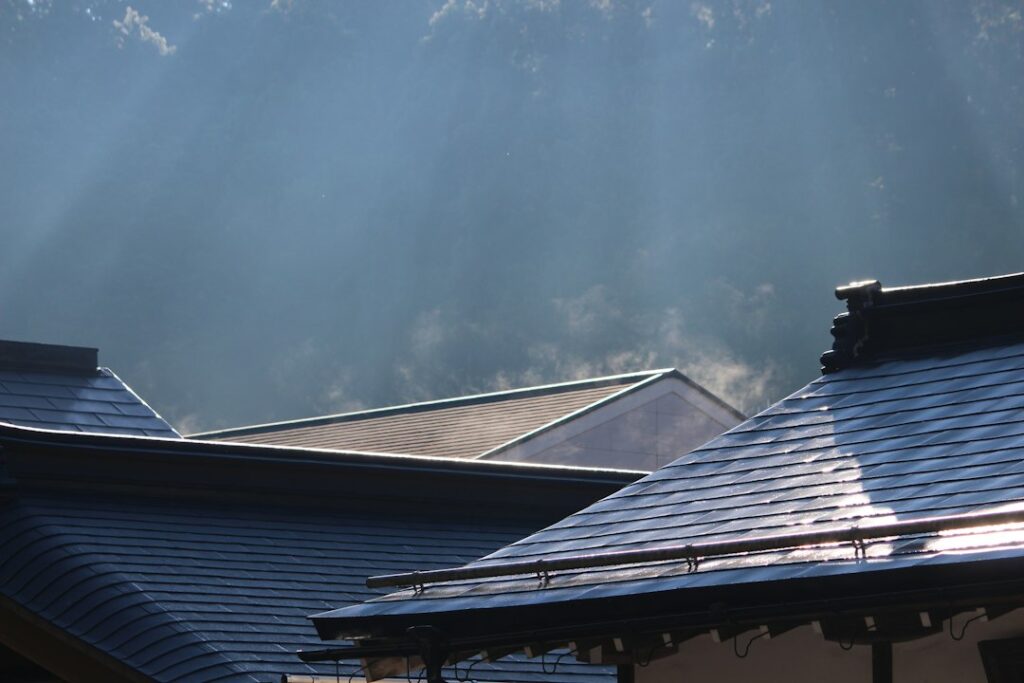 Roofing samples with rating labels beside a sunlit residential roof and insulated attic cross-section.
