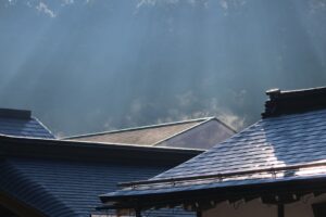 Roofing samples with rating labels beside a sunlit residential roof and insulated attic cross-section.