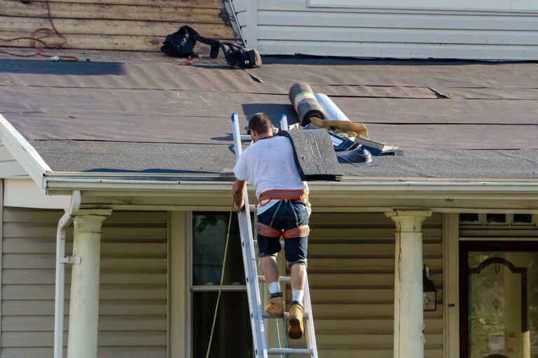 A roofer fitting metal flashing around a vent pipe on a shingled residential roof.